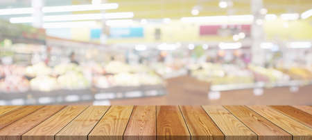 Wood table top with supermarket grocery store blurred background with bokeh light for product displayの写真素材