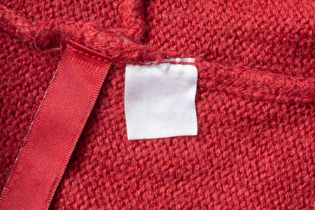 Blank laundry care clothes label on red knitted fabric texture backgroundの写真素材