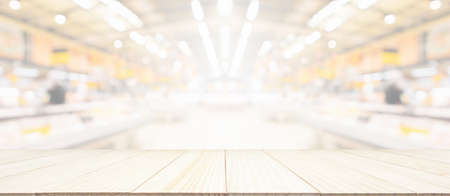 Wood table top with supermarket grocery store blurred background with bokeh light for product displayの写真素材