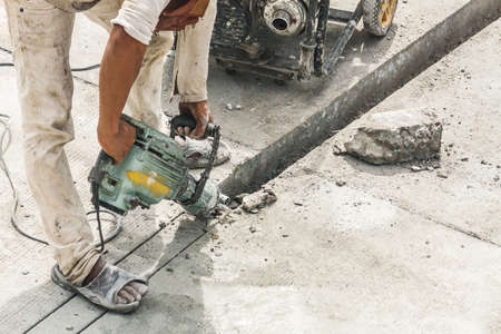 Construction worker using jackhammer drilling concrete surface
