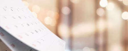 Close up white paper desk calendar with blurred bokeh background appointment and business meeting conceptの写真素材