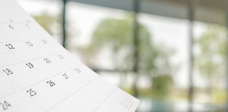 Close up white paper desk calendar with blurred bokeh background appointment and business meeting...