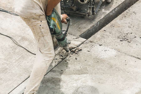 Construction worker using jackhammer drilling concrete surface