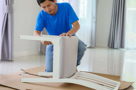 Man assembling white chair furniture at home