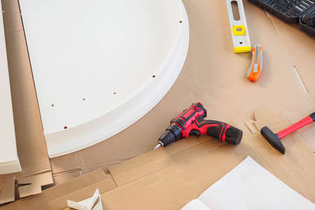Cordless screwdriver and tool on cardboard paper assembly furniture concept