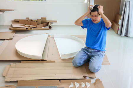 Man assembling white round table furniture at homeの写真素材