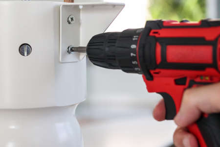 man assembling white table furniture at home using cordless screwdriverの写真素材