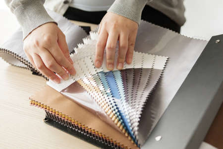 female designer with fabric color samples choosing textile for curtains