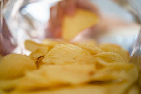 Hand picking potato chips inside snack bagの写真素材