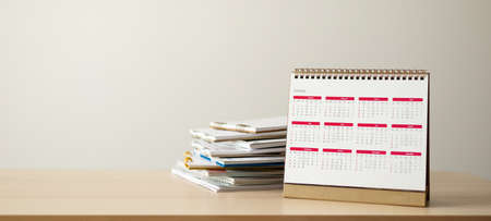 Calendar page close up on wood table with white wall background business planning appointment...