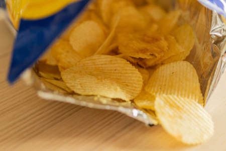 crispy potato chips in snack bag on wood tableの写真素材