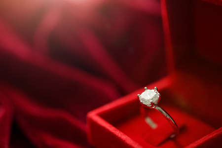 Diamond ring in jewelry gift box on red fabric backgroundの写真素材