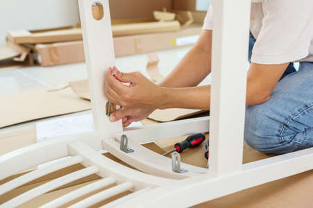 Man assembling white chair furniture at homeの写真素材
