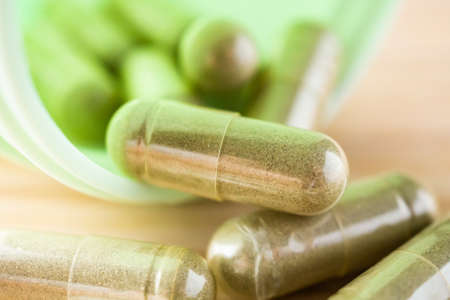 Herbal medicine capsules with bottle on wood tableの写真素材