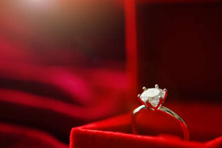 Diamond ring in jewelry gift box on red fabric backgroundの写真素材
