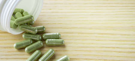Herbal medicine capsules with bottle on wood tableの写真素材