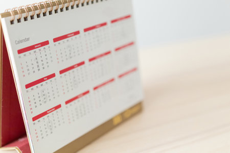 Calendar page close up on wood table with white wall background business planning appointment meeting conceptの写真素材