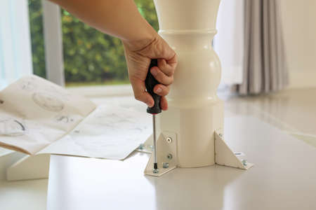 Asian man assembling white table furniture at homeの写真素材