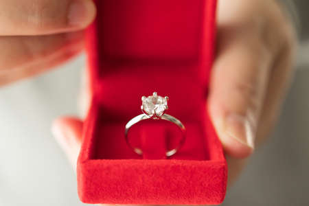 hands holding diamond ring in jewelry boxの写真素材