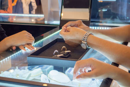 woman choosing diamond rings at jewelry store shopの写真素材