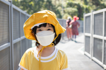 Little asian girl wearing face mask in the park New normal lifestyle travel during covid-19 pandemicの写真素材