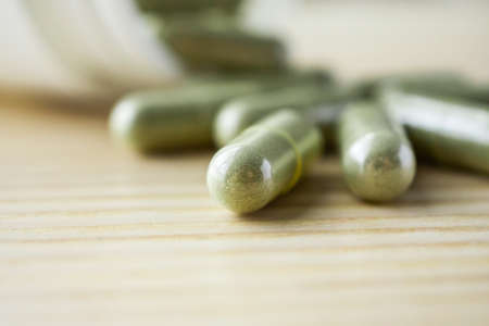 Herbal medicine capsules with bottle on wood tableの写真素材