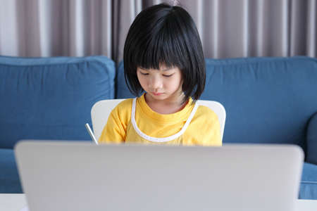 little asian girl student study online using laptop computer at home
