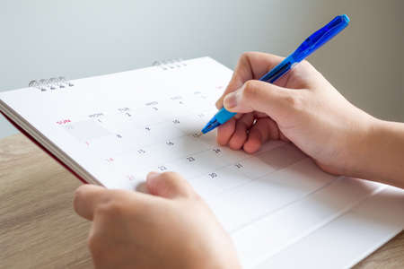 Woman hand with pen writing on calendar date business planning appointment meeting concept