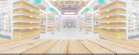 Wood table top with supermarket grocery store aisle interior blurred background with bokeh light for product displayの写真素材