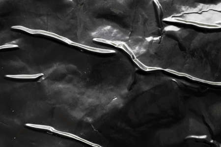 black crumpled and creased plastic poster texture background