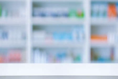 Empty white counter with pharmacy drugstore shelves blurred backgroundの写真素材