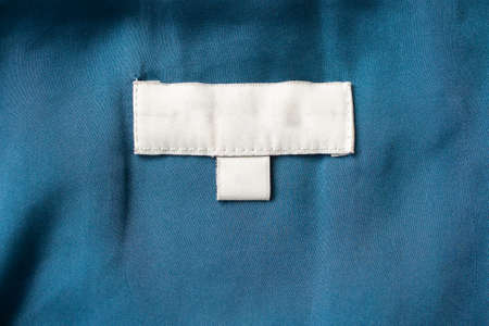 White blank laundry care clothes label on fabric backgroundの写真素材
