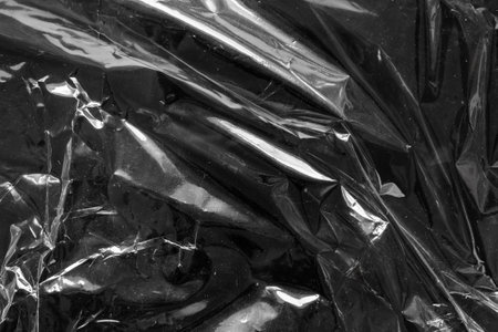 transparent plastic bag film wrap overlay texture on black backgroundの写真素材