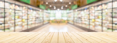 Empty wood table top with supermarket grocery store aisle and shelves blurred backgroundの写真素材