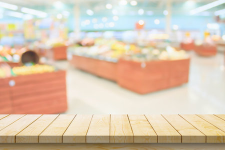 Empty wood table top with supermarket blurred background for product displayの写真素材