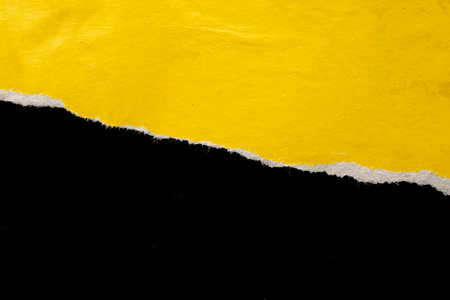 Yellow ripped paper torn edges strips isolated on black backgroundの写真素材