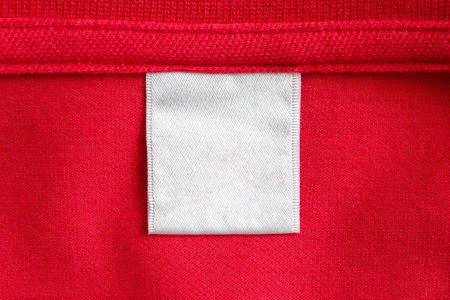 Blank white laundry care clothes label on red shirt fabric texture backgroundの写真素材