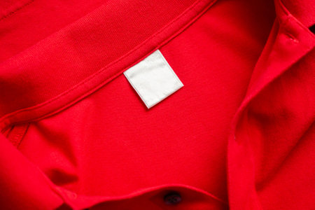 Blank white laundry care clothes label on red shirt fabric texture backgroundの写真素材