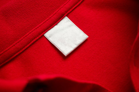 Blank white laundry care clothes label on red shirt fabric texture backgroundの写真素材