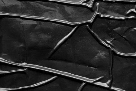 black crumpled and creased plastic poster texture background
