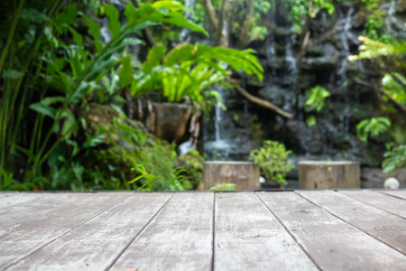 Empty wood table top with blur green tropical garden background for product displayの写真素材