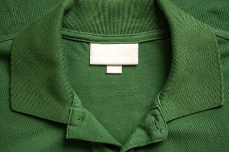 Blank white laundry care clothes label on green shirt fabric texture backgroundの写真素材