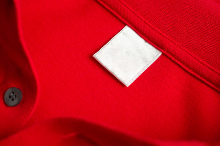 Blank white laundry care clothes label on red shirt fabric texture backgroundの写真素材