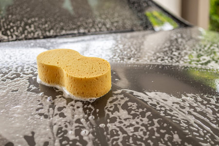 car cleaning and washing with yellow sponge and foam soapの写真素材