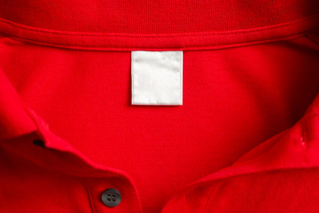 Blank white laundry care clothes label on red shirt fabric texture background