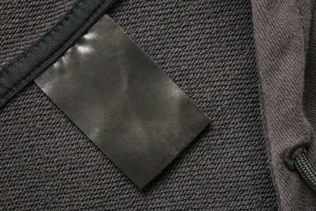 Blank black laundry care clothes label on black fabric texture background