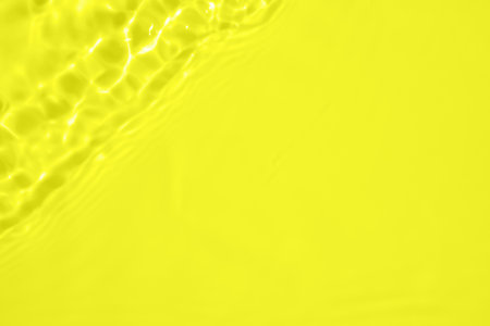 Abstract transparent water shadow surface texture natural ripple on yellow backgroundの写真素材