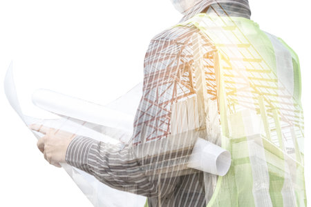 Double exposure image of professional engineer in protective helmet and blueprints paper at building construction siteの写真素材