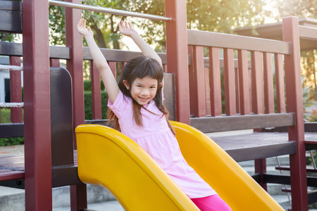 Cute asian girl playing on the slide in the playgroundの写真素材