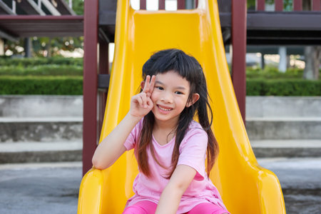 Cute asian girl playing on the slide in the playground